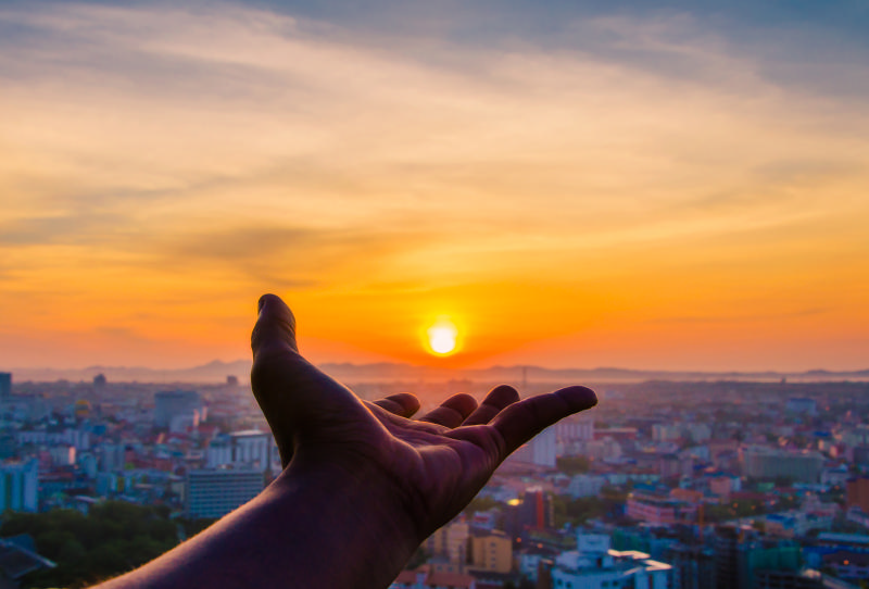 Hand extended towards the setting sun